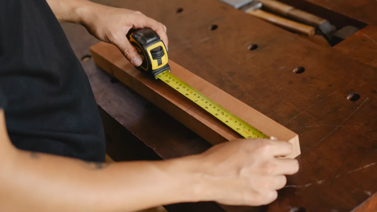 How Far Should a Septic System Be From a House, Well, or Property Line? Person measuring a wooden board with a tape measure
